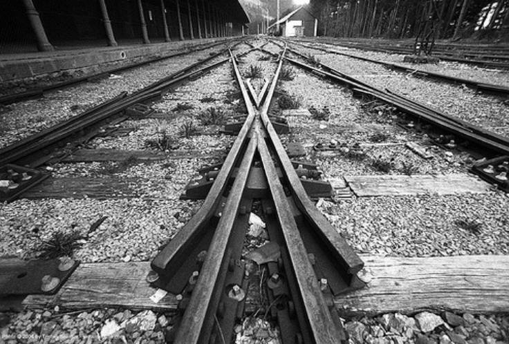 Bu görsel siyah beyaz bir fotoğraf. Foroğrafta iki tren rayı gözüküyor ve raylar sola ya da sağa geçiş için birbirine bağlanıyor.